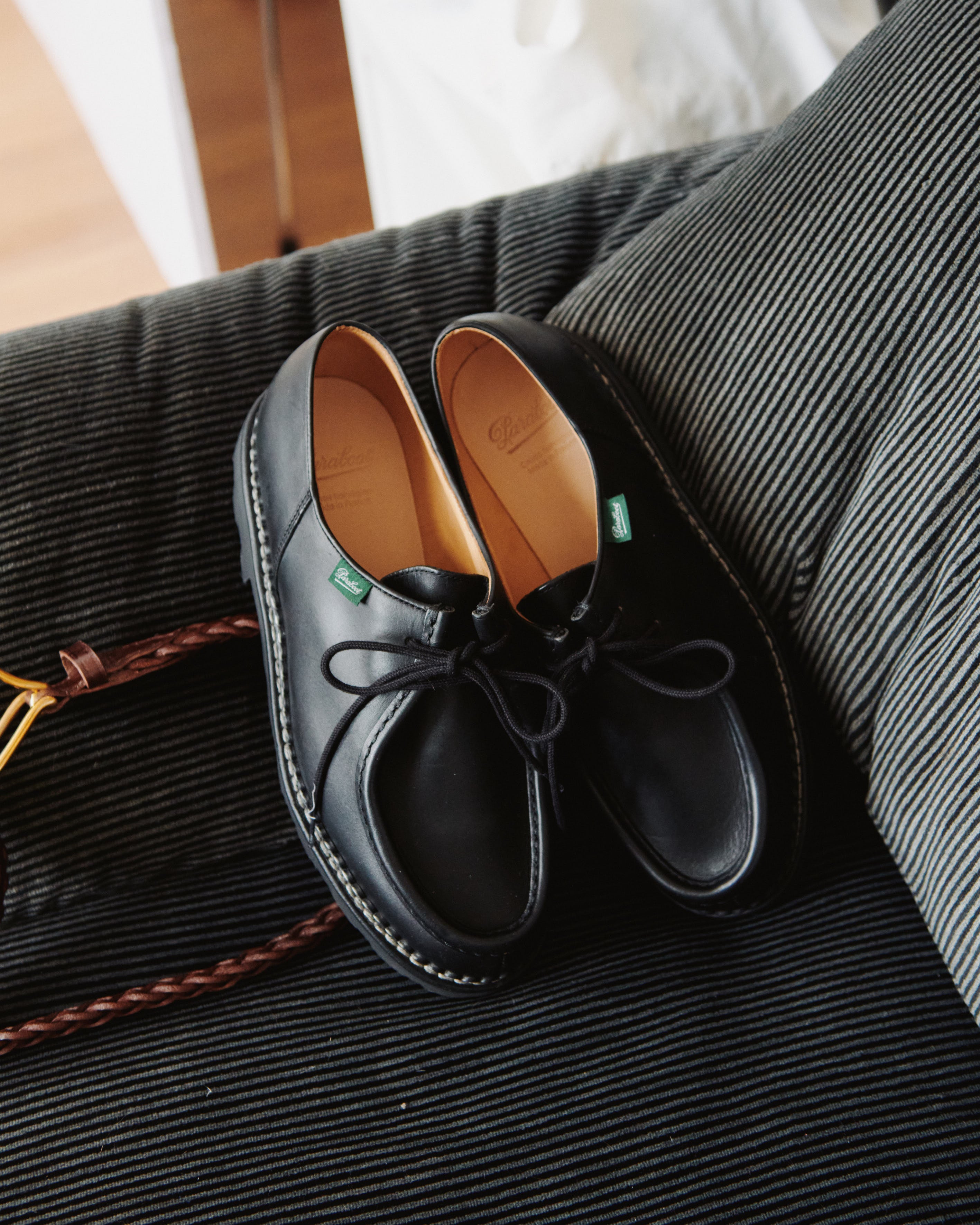 Paraboot Michael shoes in Black Lisse leather styled on a corduroy chair