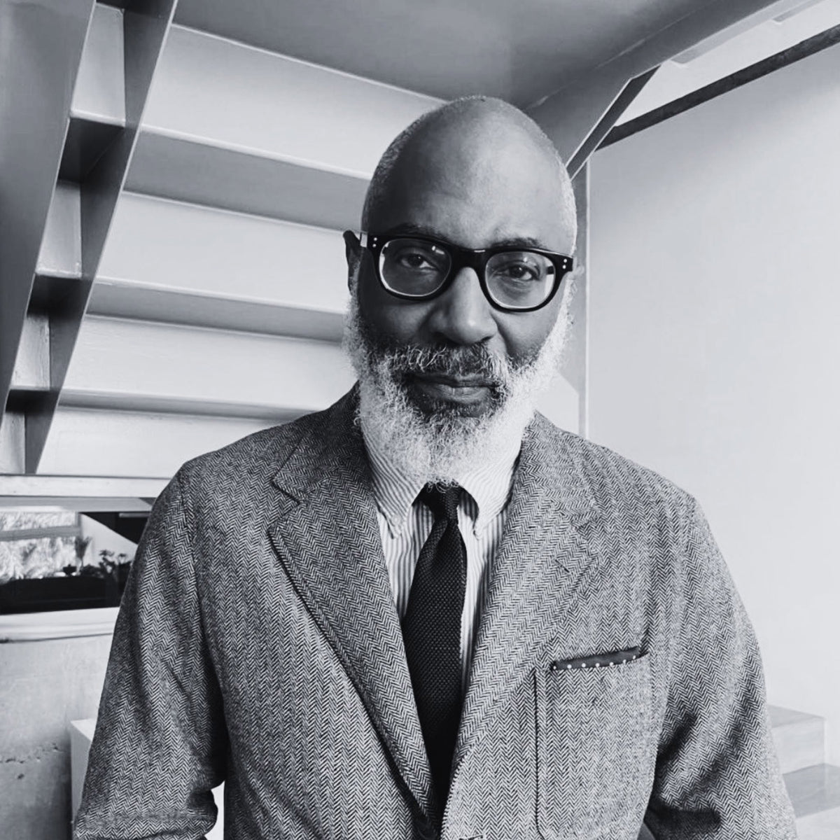 Portrait of Jason Jules wearing a tailored jacket, Oxford shirt and knit tie