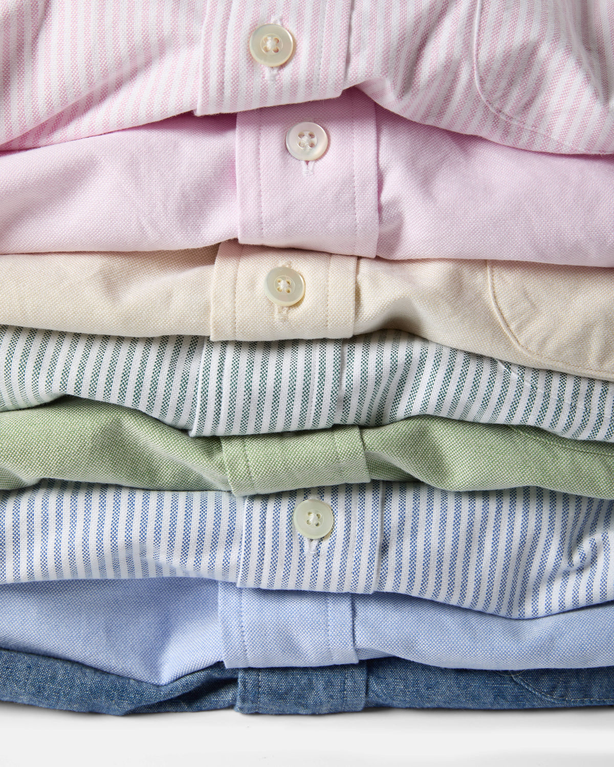 Flat lay of stacked Kamakura Vintage Ivy Oxford button-down shirts in solid colours and university stripes